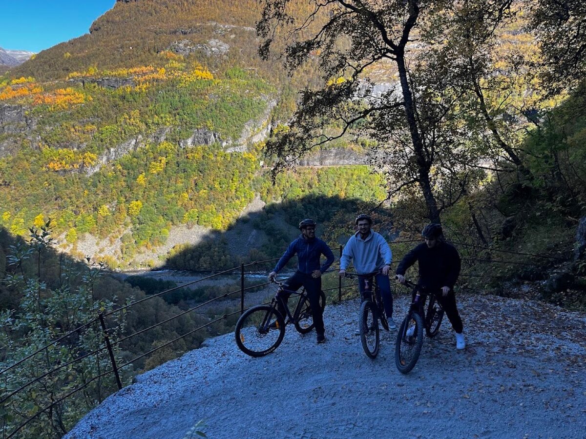 Three cyclists on the gravel mountain switchbacks of Rallarvegen above Flåm valley